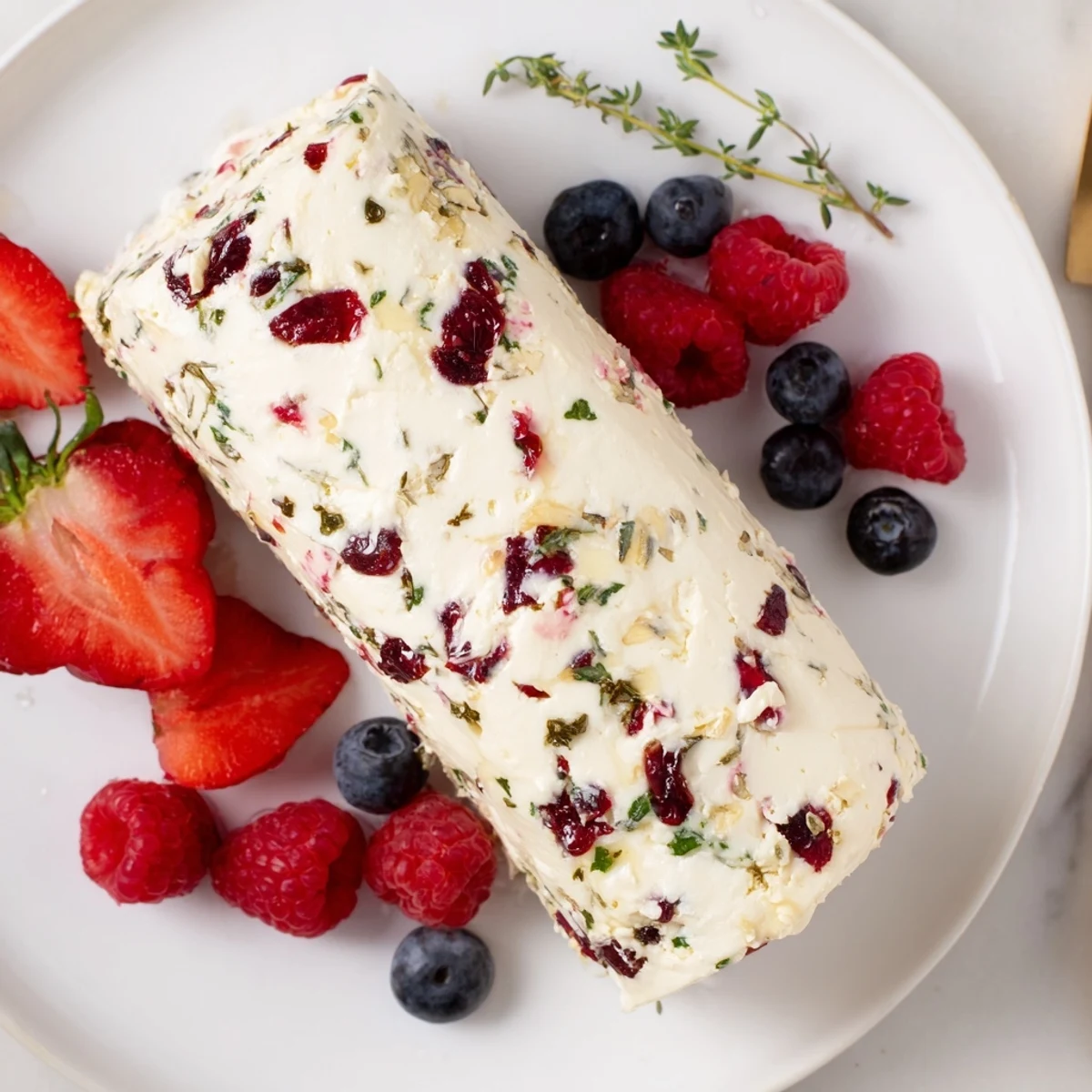 Vibrant photo showcases a creamy Cranberry & Goat Cheese Log surrounded by fresh, colorful berries.
