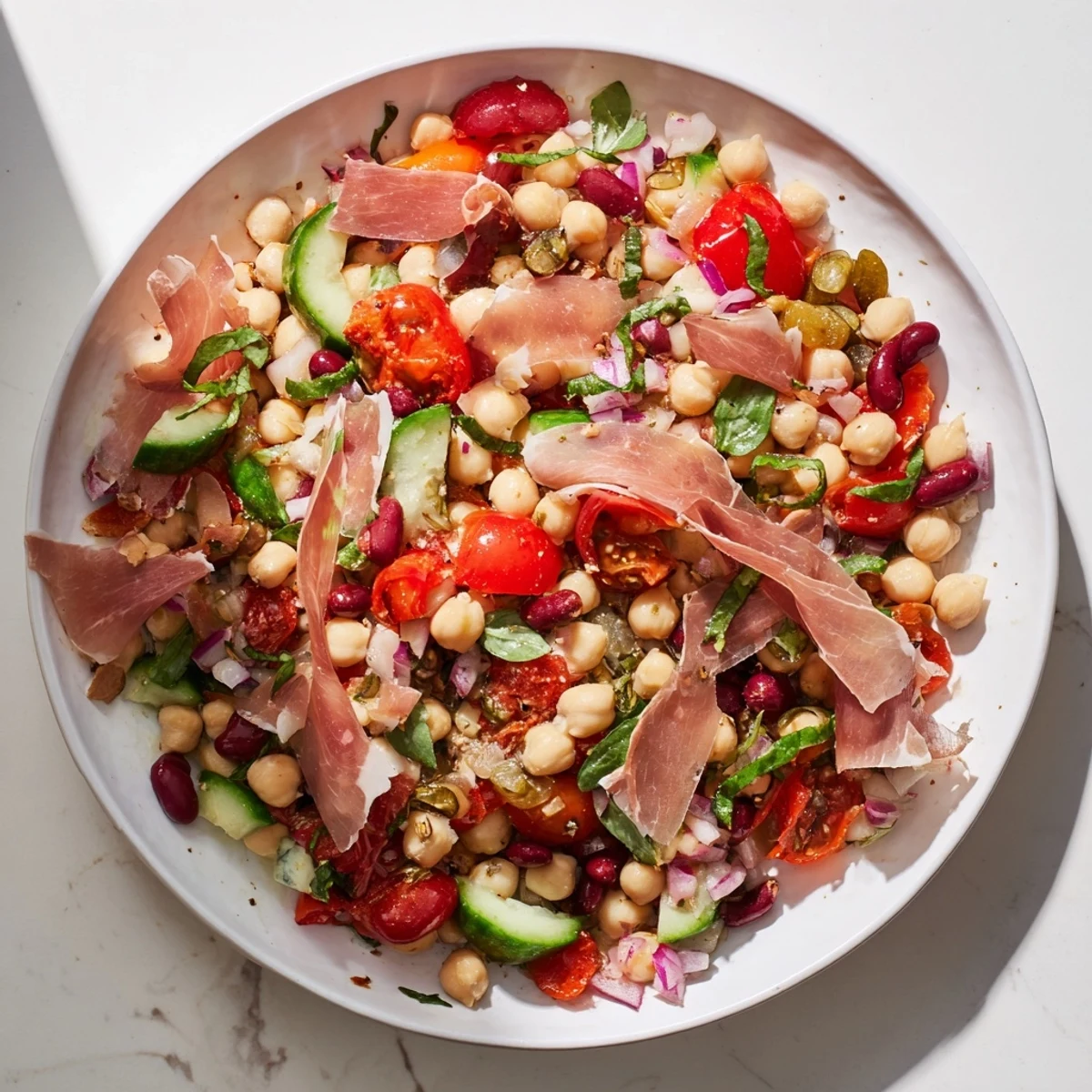 Fresh, chilled Dense Bean Salad with Prosciutto, featuring bright vegetables and salty Italian prosciutto topping.