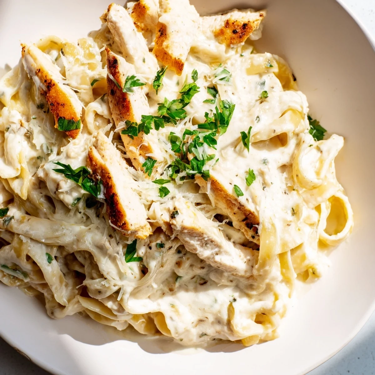 Skillet Chicken Alfredo features golden chicken strips and fettuccine in a creamy Parmesan sauce, garnished with fresh parsley for a comforting Italian-American weeknight dinner.  