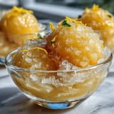 Vibrant limoncello sorbet in a chilled glass, garnished with fresh mint leaves and lemon zest.  