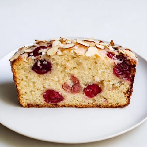 A freshly baked Cherry Almond Loaf Cake with a golden crust and glistening cherries on top.