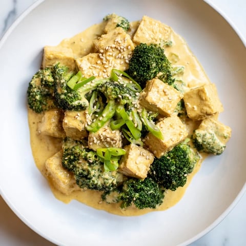Golden, baked Cheesy Baked Tofu and Broccoli, coated in creamy sauce, garnished with sesame seeds.