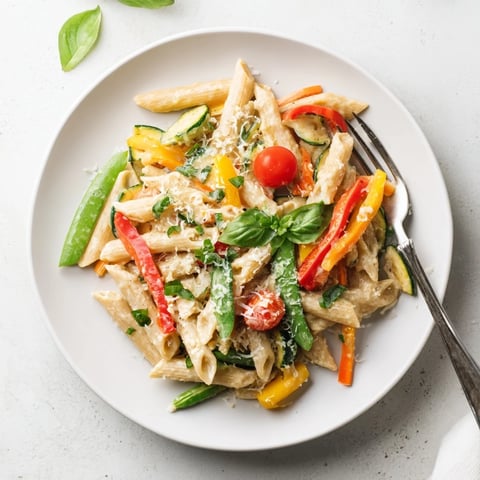 Creamy One-Pot Pasta Primavera with fresh zucchini, bell peppers, and cherry tomatoes in a rich Parmesan sauce.  
