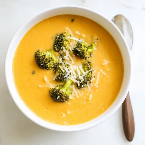 A comforting bowl of Broccoli Cheddar Soup featuring smooth, creamy texture and melted sharp cheddar cheese garnish.  