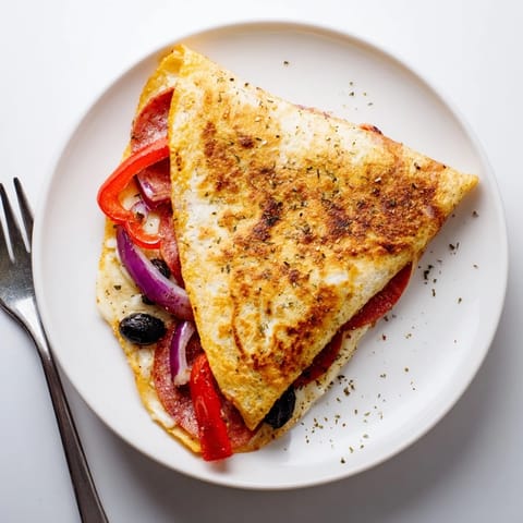 A pan-toasted Tortilla Pizza Wrap cut in half, revealing a cheesy interior of pepperoni, red onion, and olives.