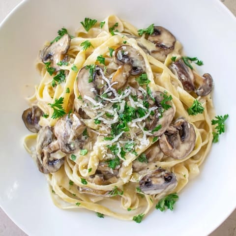 Hearty Creamy Mushroom Alfredo served warm in a skillet, with al dente pasta and extra Parmesan garnish.