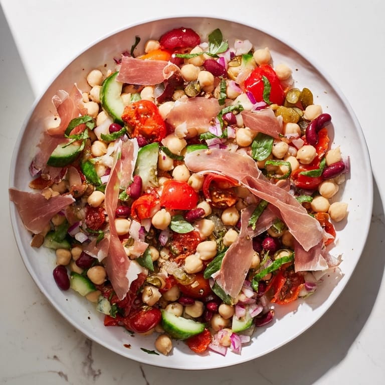 Fresh, chilled Dense Bean Salad with Prosciutto, featuring bright vegetables and salty Italian prosciutto topping.