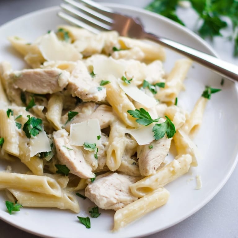 Freshly chopped parsley and extra grated Parmesan top a warm plate of Roasted Garlic Chicken Penne, promising rich, comforting flavors.