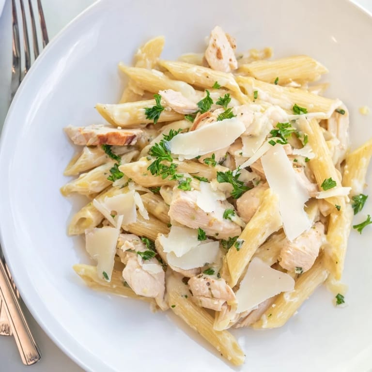 Tender roasted chicken pieces and silky garlic cream sauce cling to each ridge of penne pasta in a satisfying Italian-American main dish.